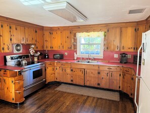 Una cocina con armarios de madera, una estufa de acero inoxidable, un fregadero y un ventanal con vistas.