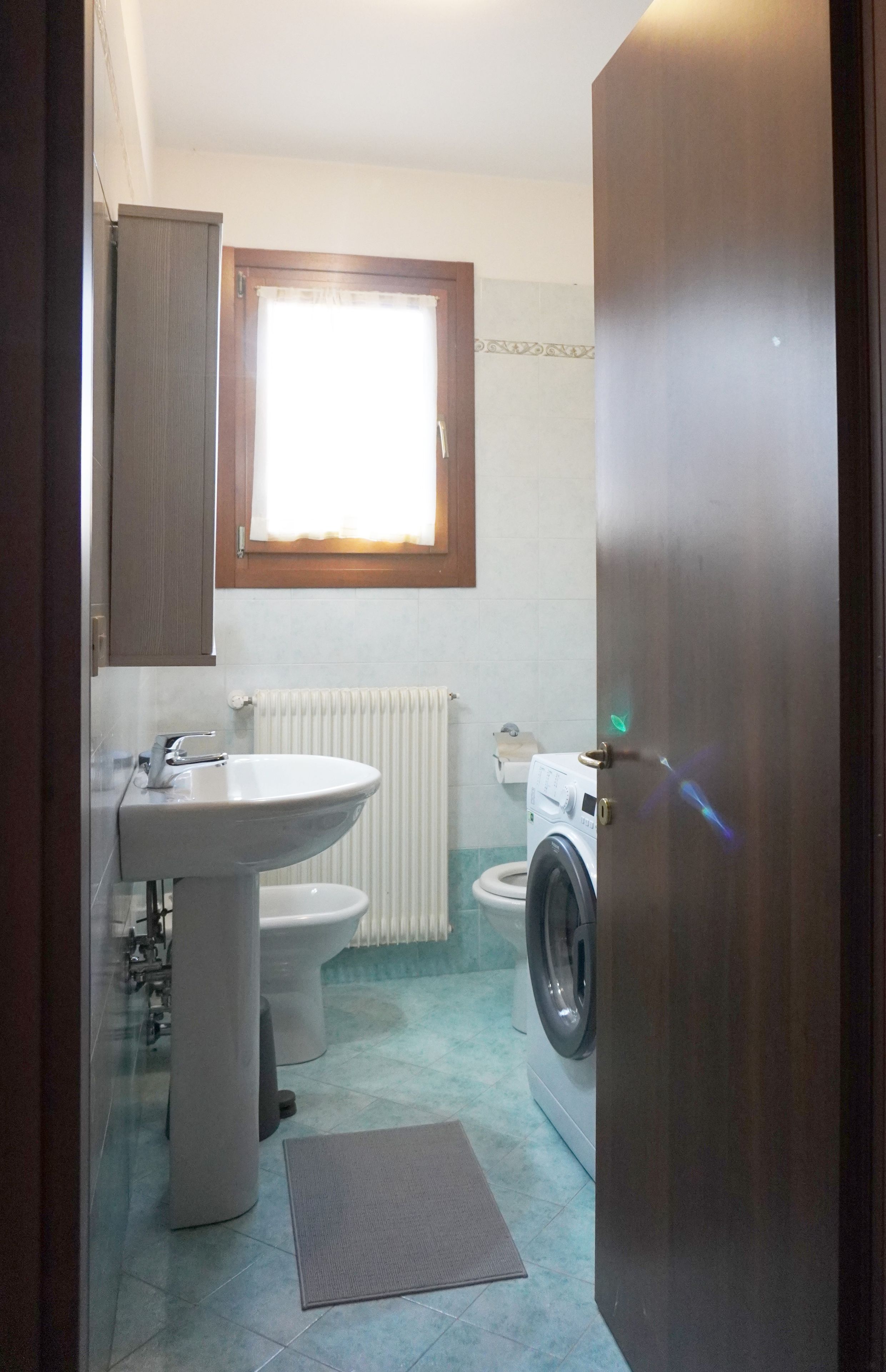 Een kleine badkamer met een wastafel, toilet en wasmachine.