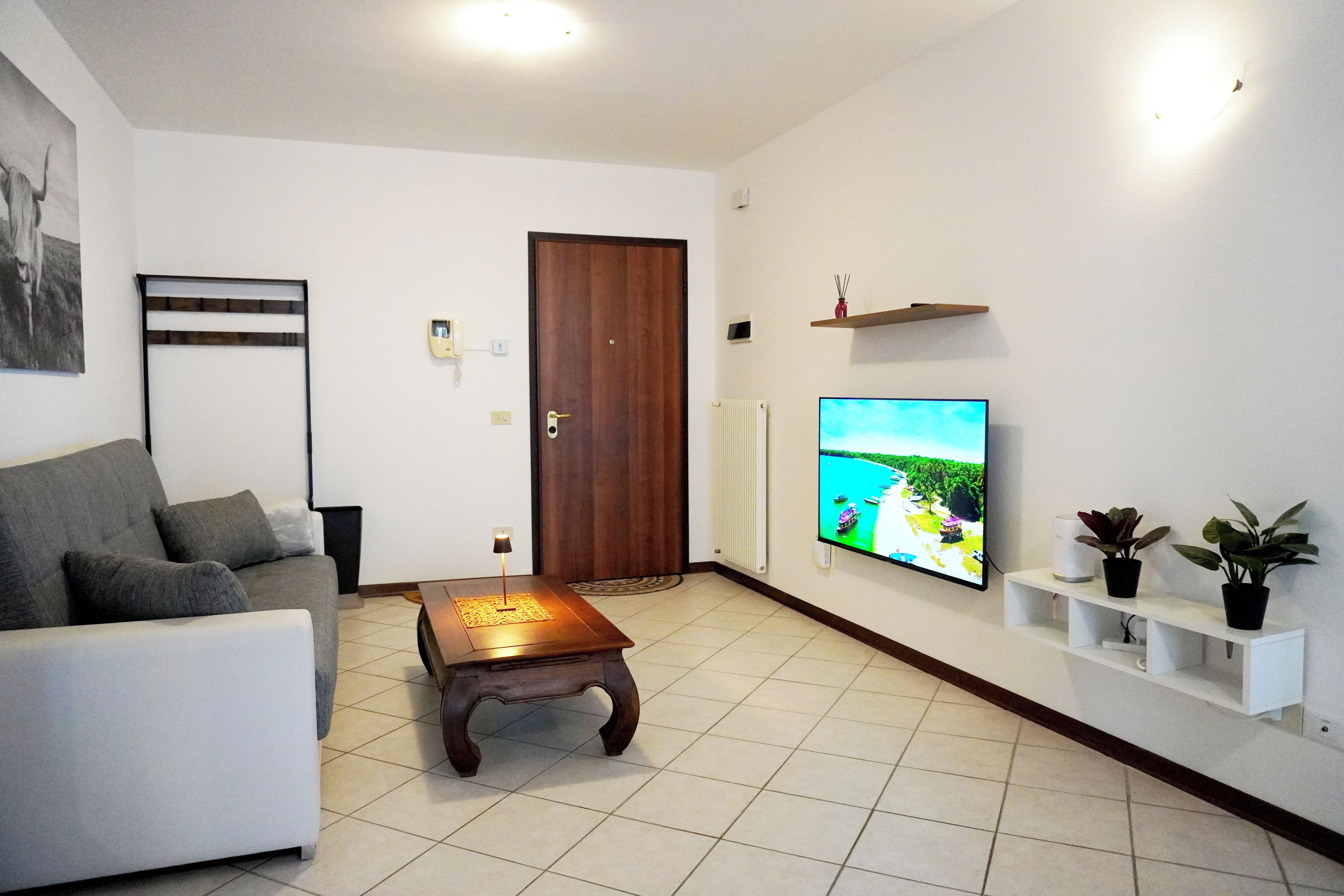 A living room with a sofa, coffee table, TV, and a door.