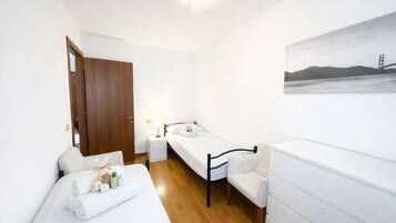 A hotel room with a bed, bedside table, chair, and a painting on the wall.