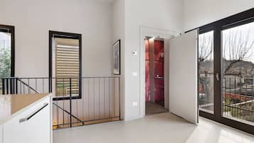 Ein modernes Interieur mit einer Treppe, einer Tür zu einem roten Raum und einem großen Fenster mit Blick.