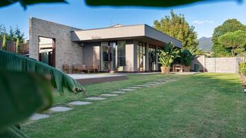 A modern house with a stone facade, a covered patio, and a well-maintained lawn.
