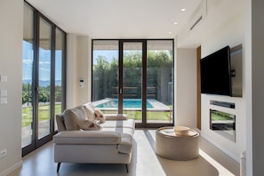 A modern living room with a sofa, a round coffee table, and a TV mounted on the wall.
