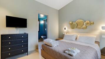 A bedroom with a bed, a dresser, a flat-screen TV, and a wall-mounted light fixture.