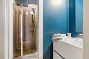 Un bagno con doccia vetrata, lavandino bianco e parete blu.