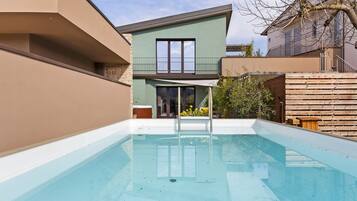 A swimming pool with a clear view of a modern house in the background.
