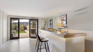 Eine moderne Küche mit Bar, einer Schiebetür zu einer Terrasse und Blick ins Freie.