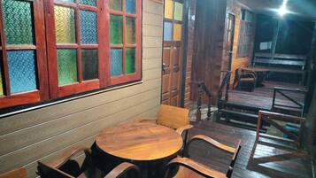 A wooden interior with a round table and chairs, a staircase, and a door with glass panels.