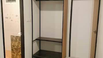 A room with a white air conditioning unit, a wooden door, a tiled floor, and a brown mat.