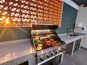 An outdoor kitchen with a grill, a sink, and a decorative lattice wall. - 1BR condo in La Cruz de Huanacaxtle with pool, gym, WiFi, and AC. (Bahia de Banderas)