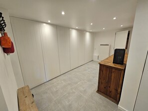 A hallway with a wooden bench, a white door, and a small wooden table with a black object on it. - Beautiful cabin for 12–14 people. Winter/Summer in Vaujany, the Greater Alpe d'Huez Area (Vaujany)