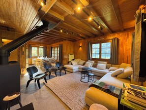 A cozy cabin interior with a fireplace, wooden walls, a sofa, and a dining area. - Beautiful cabin for 12–14 people. Winter/Summer in Vaujany, the Greater Alpe d'Huez Area (Vaujany)