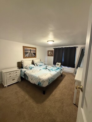 A bedroom with a bed, a nightstand, a dresser, a window with curtains, and a ceiling light. - Charming 3-bedroom house Cincinnati (Cincinnati)