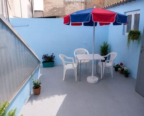 A small outdoor patio with a table and chairs, a blue and red umbrella, and potted plants. - petite maison traditionnelle à l ancienne médina à Casablanca (Casablanca)
