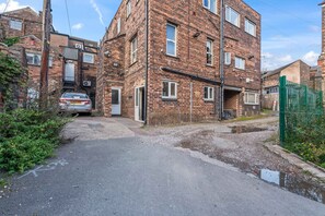A multi-story brick building with a narrow driveway leading to a parked car. - Spacious Burslem Studio Perfect for Contractors (Stoke-on-Trent)