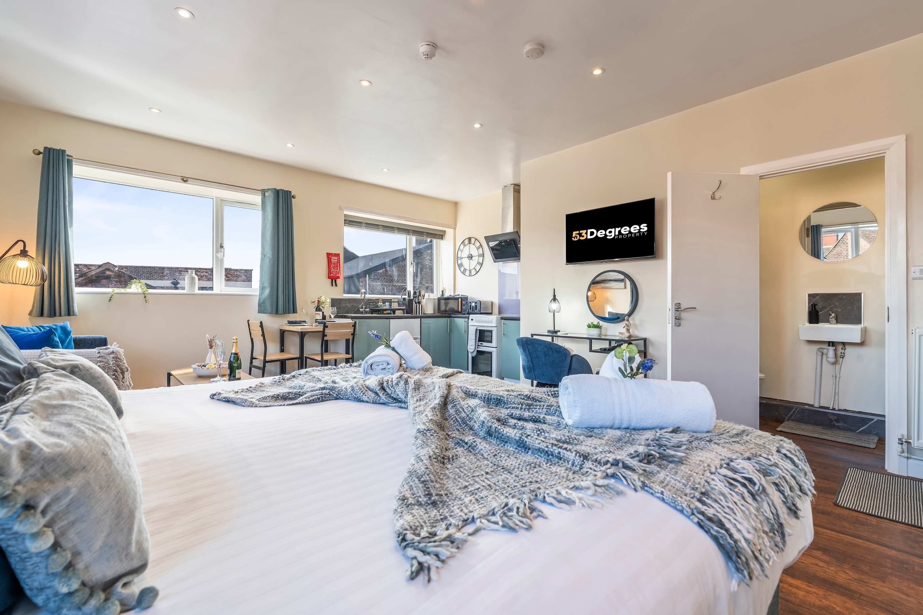 Una habitación de hotel moderna con una cama grande, una kitchenette, un comedor y un baño.