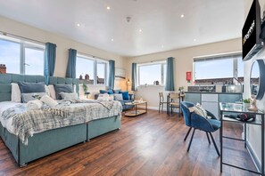 A modern apartment with a large bed, a dining area, and a kitchen. - Spacious Burslem Studio Perfect for Contractors (Stoke-on-Trent)