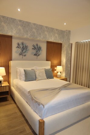 A hotel room with a large bed, two bedside tables, and a headboard with wall art. - Elegant and Sophisticated Apartment Near the Beach (Punta Cana)
