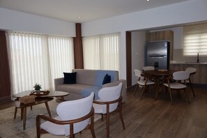 Ein modernes Wohnzimmer mit einer Couch, Sesseln, einem Couchtisch und einem Essbereich mit Tisch und Stühlen.