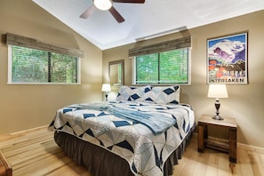 A bedroom with a bed, two bedside lamps, a ceiling fan, and a poster on the wall. - Smoky Mtn Escape Hot Tub Fire Pit Game Room (Gatlinburg)