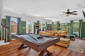 A pool table in a room with a sofa, a ceiling fan, and a view of the outdoors. - Wineberry Ridge Hot Tub Sauna Grill Views (Asheville)