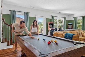 A pool table in a room with a staircase, a sofa, and arcade machines. - Wineberry Ridge Hot Tub Sauna Grill Views (Asheville)