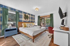 A modern bedroom with a large bed, a desk, a TV, and a window with curtains. - Wineberry Ridge Hot Tub Sauna Grill Views (Asheville)