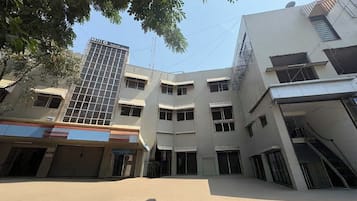 Un edificio de varios pisos con fachada plana y varias entradas a nivel de calle, y un cartel de hotel llamativo.