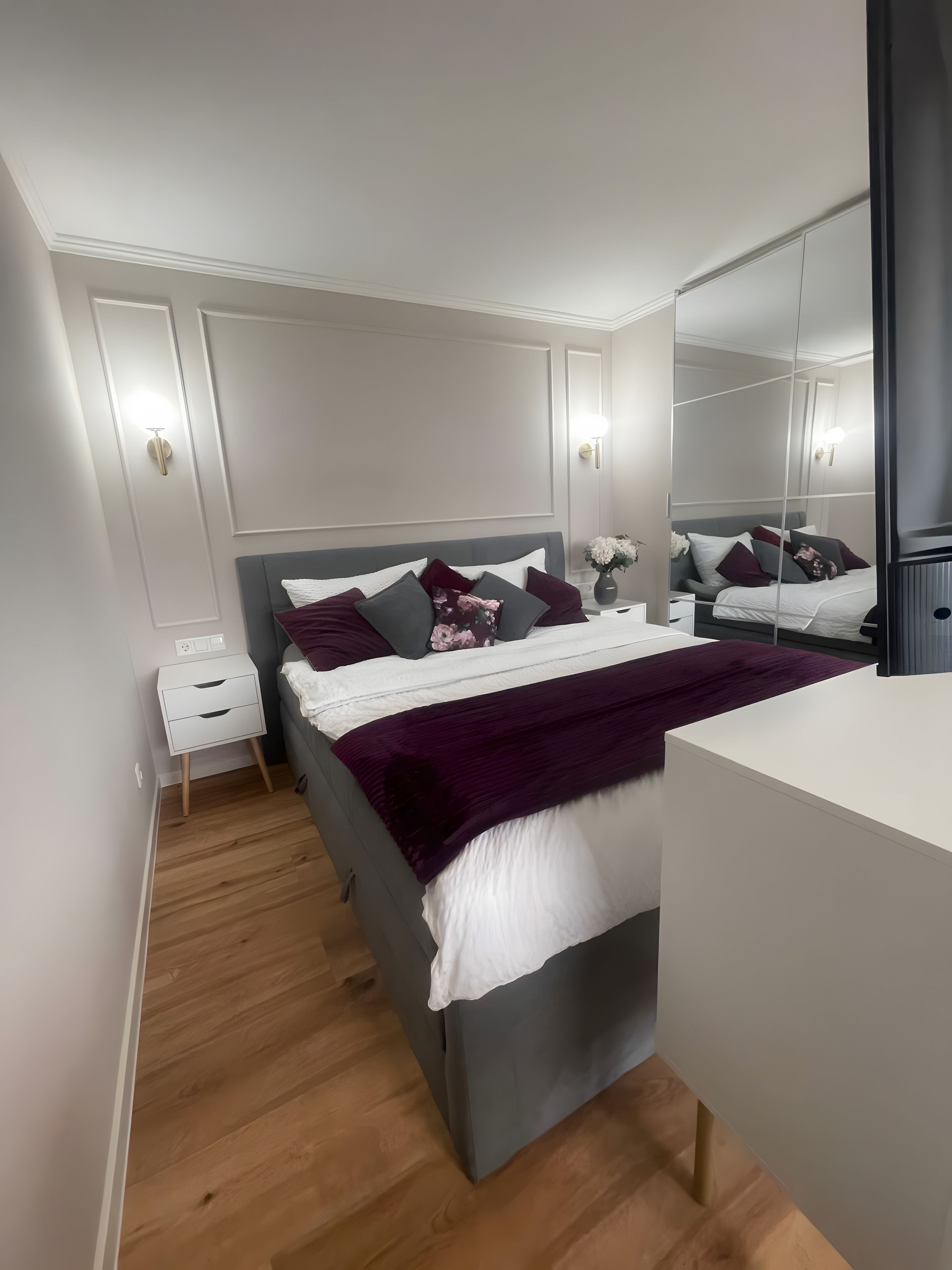 Ein modernes Schlafzimmer mit einem Bett, einem Nachttisch und einem großen Spiegel.