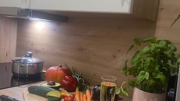 A kitchen counter with a cutting board, vegetables, a glass of water, a plate of salmon, and a potted plant.