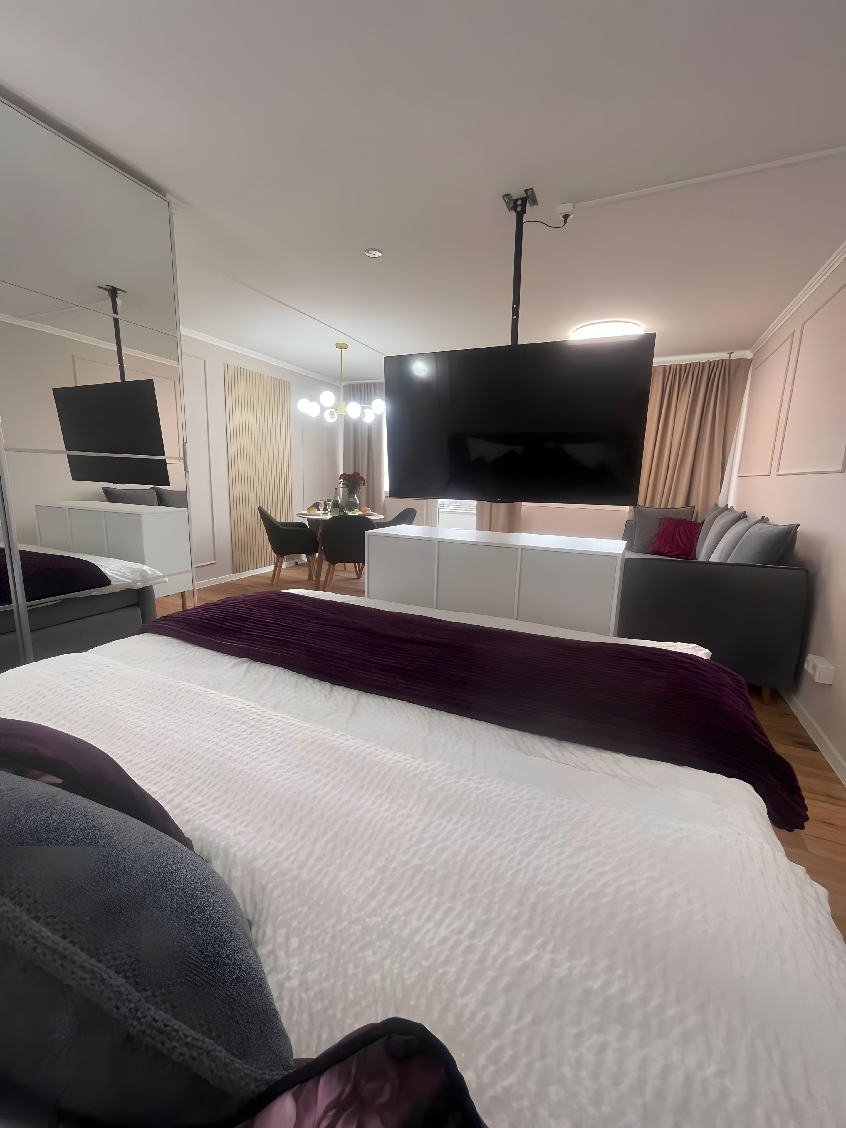 Ein modernes Hotelzimmer mit einem großen Bett, einem Flachbildfernseher, einem Schreibtisch mit Stuhl und einer Couch.