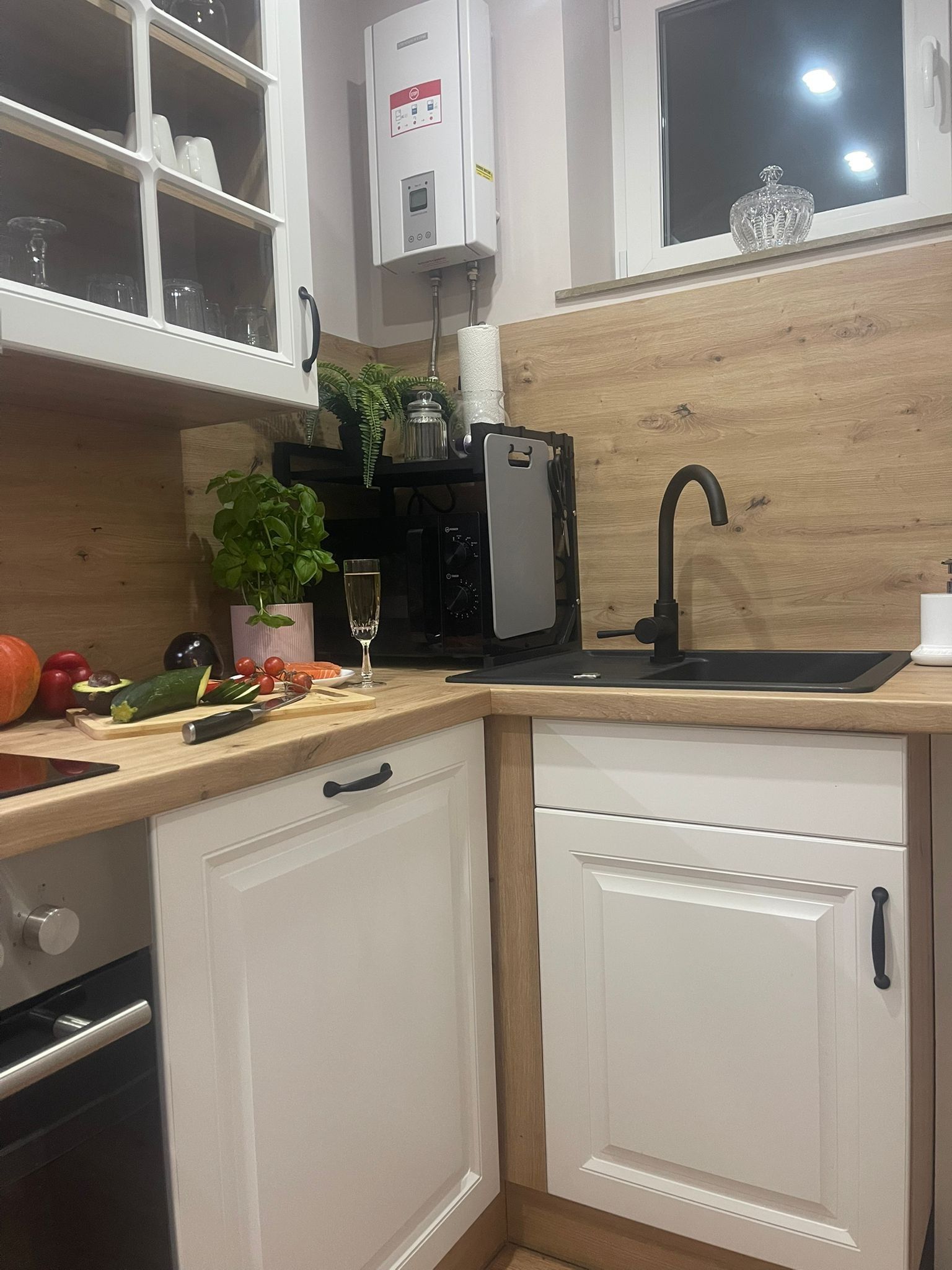 A kitchen with a wooden countertop, a sink, a coffee machine, and cabinets.