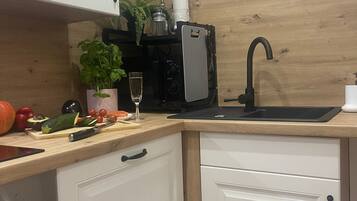 A kitchen with a wooden countertop, a sink, a coffee machine, and cabinets.