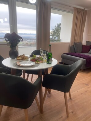 A dining area with a table set for two, a bottle of wine, and a vase of flowers. - Apartment 'See und Bergblick 58 mit Indoorpool' (Oberteuringen)