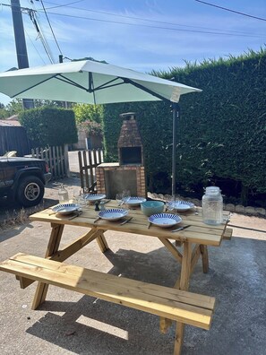A wooden picnic table with a pizza oven and a green umbrella. - An Autumn Getaway in Cap Ferret, Amid Pine Trees and the Lagoon (Lège-Cap-Ferret)