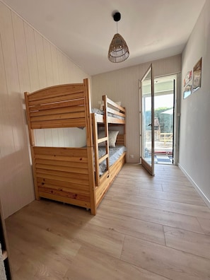 A room with a bunk bed, a hanging light fixture, and a door leading to an outdoor area. - An Autumn Getaway in Cap Ferret, Amid Pine Trees and the Lagoon (Lège-Cap-Ferret)