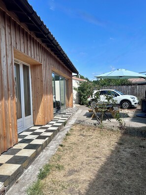 A wooden house with a checkered pathway leading to a car parked in the driveway. - An Autumn Getaway in Cap Ferret, Amid Pine Trees and the Lagoon (Lège-Cap-Ferret)