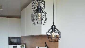 A modern kitchen with a wooden countertop, a white toaster, and two black geometric pendant lights.