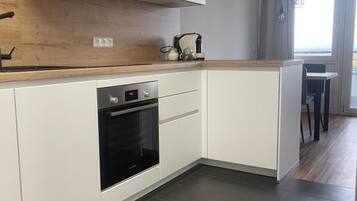 A modern kitchen with white cabinetry, a built-in oven, and a wooden countertop.