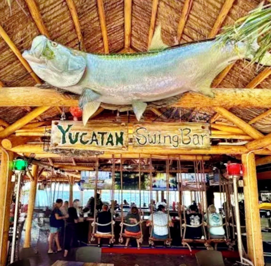 A swing bar with a sign reading 'Yucatan SwingBar' and a large fish decoration above it.
