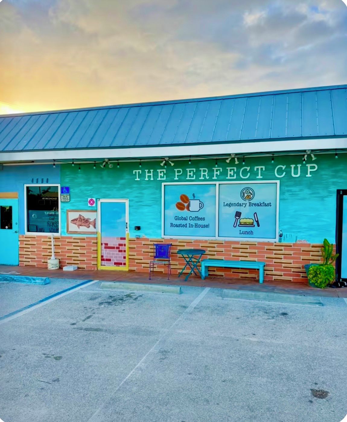 A building with a sign reading 'THE PERFECT CUP' advertising a menu including global coffees, roasted in-house, and a legendary breakfast.