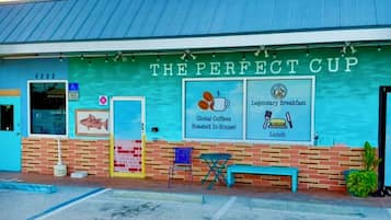 A building with a sign reading 'THE PERFECT CUP' advertising a menu including global coffees, roasted in-house, and a legendary breakfast.