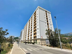 A multi-story hotel with balconies, a paved sidewalk, and a clear sky. - Alula Apartments 2 (Bar)