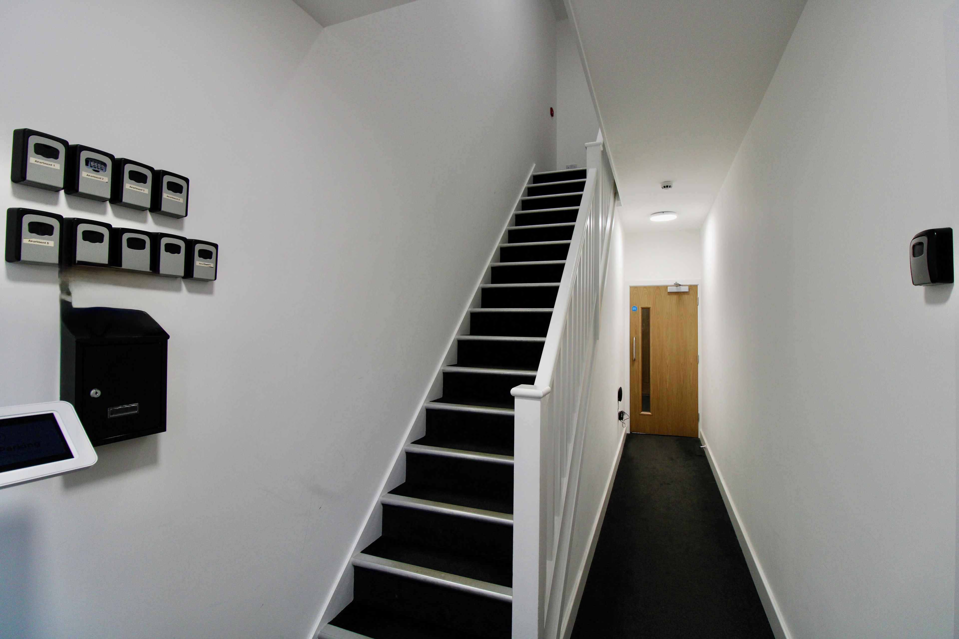 A staircase in a hallway with a door at the end.