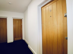 A hallway with three wooden doors, each marked with a number. - Apartment 6 @10 Short-stays (Basingstoke)