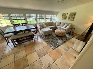 A living room with a sectional sofa, a dining table with chairs, a coffee table, and a rug. - Baton Rouge Overpass Oasis - Perfect for Tiger Game day (Baton Rouge)