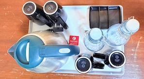 Una bandeja con cafetera, hervidor, jarra de vidrio y varias botellas, probablemente con condimentos o bebidas.