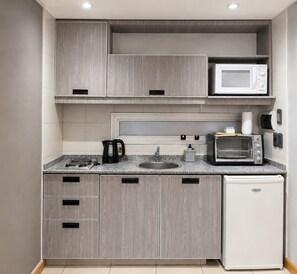 Eine kleine Küche mit Mikrowelle, Toaster, Wasserkocher und kleinem Kühlschrank.