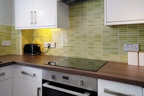 A kitchen with a built-in oven, a toaster, and a backsplash with green tiles. - Cosy Keswick 1BR|Sleeps 2| by Stay with Us (Keswick)