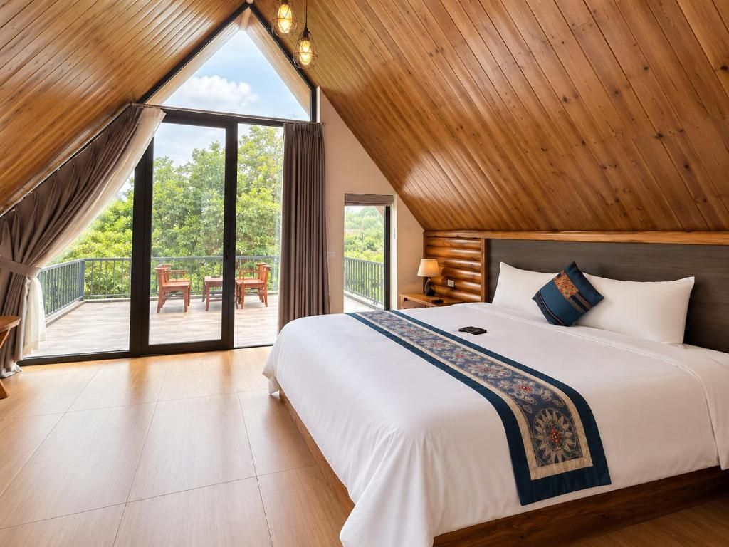 Un dormitorio con una cama grande, techo de madera y vistas al exterior.